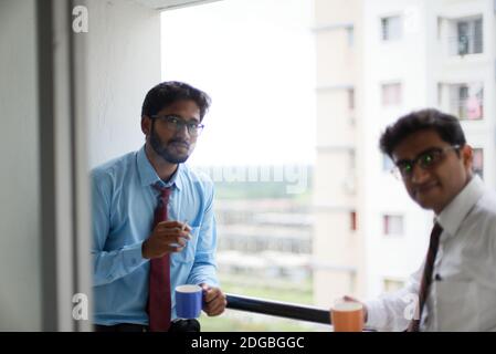 Incontri aziendali con caffè/tè e sigaretta tra giovani ed energici Dirigenti/funzionari/dirigenti indiani bengalesi sul balcone dell'edificio degli uffici Foto Stock