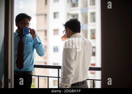 Incontri aziendali con caffè/tè e sigaretta tra giovani ed energici Dirigenti/funzionari/dirigenti indiani bengalesi sul balcone dell'edificio degli uffici Foto Stock