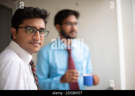 Incontri aziendali con caffè/tè e sigaretta tra giovani ed energici Dirigenti/funzionari/dirigenti indiani bengalesi sul balcone dell'edificio degli uffici Foto Stock