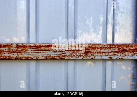 Ferro recinzione arrugginita. Superficie in metallo ondulato bianco o zinco o acciaio galvanizzato sullo sfondo verticale Foto Stock
