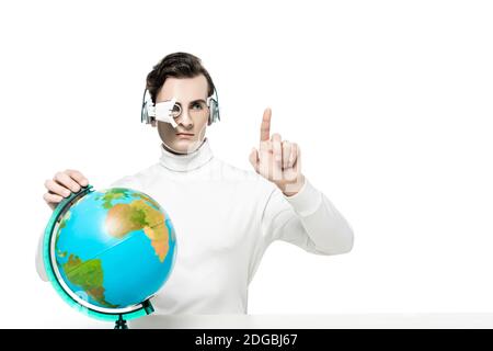 Cyborg con obiettivo digitale e cuffie che puntano con le dita vicino globo isolato su bianco Foto Stock