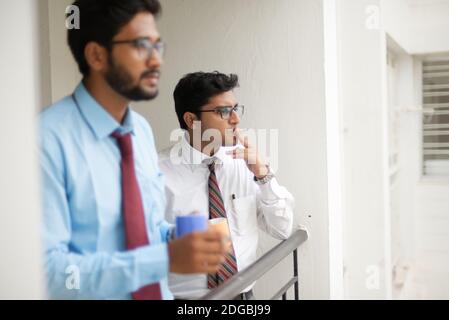 Incontri aziendali con caffè/tè e sigaretta tra giovani ed energici Dirigenti/funzionari/dirigenti indiani bengalesi sul balcone dell'edificio degli uffici Foto Stock