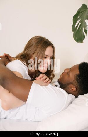 Ritratto di una coppia mista sdraiata su un divano agguato Foto Stock