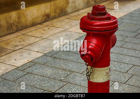 Idrante antincendio rosso bianco protezione della città su un sfondo di piastrelle grigie design urbano Foto Stock