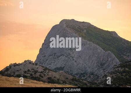 La montagna più alta con ripidi pendii all'alba o alla luce del tramonto cielo rosa pallido Foto Stock