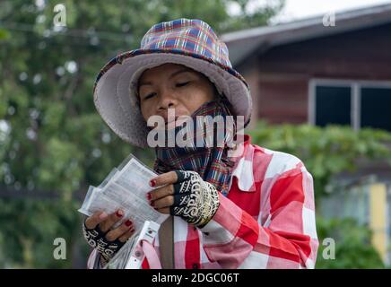 SAMUT PRAKAN, THAILANDIA, 14 2020 MARZO, un venditore controlla il biglietto della lotteria su una strada Foto Stock