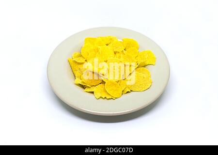 Piatto con spuntini di mais giallo fiocchi su sfondo bianco sano colazione, pranzo con spuntini Foto Stock