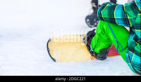 Vista ravvicinata delle gambe maschili sullo snowboard Foto Stock