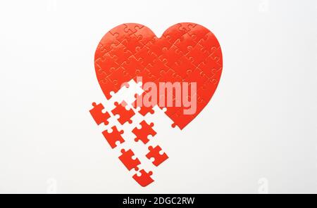 Puzzle a forma di cuore con pezzi sparsi su sfondo bianco Foto Stock
