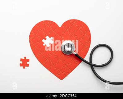 Stetoscopio giacente su puzzle a forma di cuore con pezzo mancante Foto Stock