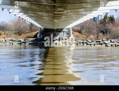 Sotto piccole travi di ponte in metallo che attraversano il fiume fangoso, a Toronto, Canada. Foto Stock