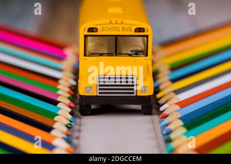 Matite colorate e autobus giallo, ritorno a scuola. Foto Stock