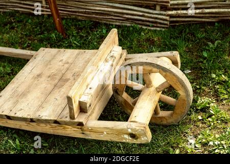 Tradizionale vecchio carrello di legno con una ruota al centro si trova sull'erba per la consegna del carico Foto Stock