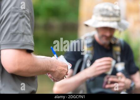 Poliziotto o Ranger che controlla la licenza di pescatore nel fiume. Ispezione della pesca. Legge. Foto Stock