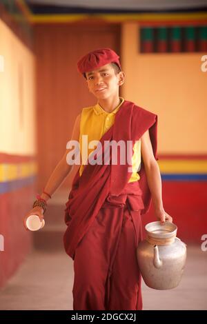 Giovane monaco novizio con una brocca di tè e una tazza, monastero di Hemis, Hemis, Ladakh, Jammu e Kashmir, India Foto Stock