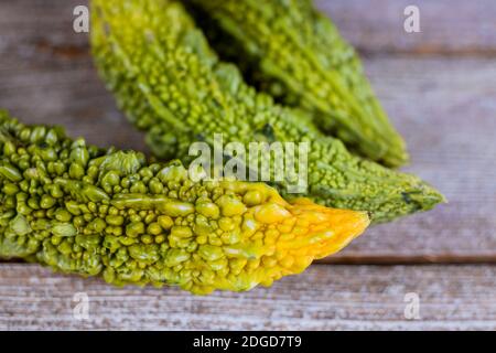 Melone amaro fresco di erbe verdi organiche o vegetali, cetriolo amaro o cetriolo amaro su vecchio sfondo di legno Foto Stock