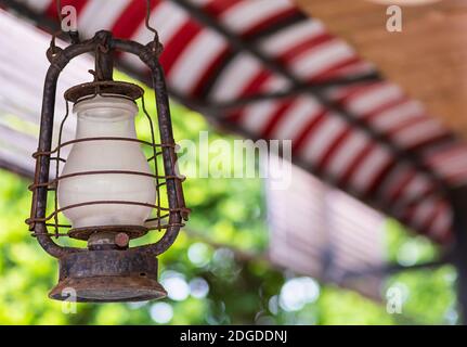 Vecchia lampada a olio con vetro bianco con spazio per la copia su uno sfondo sfocato tetto in tessuto polorussaya rosso wh Foto Stock