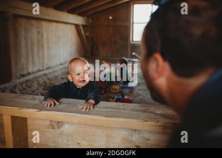 Adorabile ragazzo sorridendo a papà in un sandbox esterno coperto in inverno Foto Stock