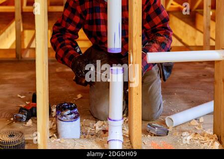 Idraulico applicazione di colla al tubo in PVC in costruzione in nuovo casa Foto Stock