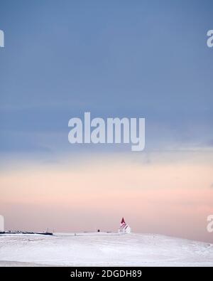 La cabina solitaria si trova su una collina innevata in inverno Cielo rosa in Islanda Foto Stock