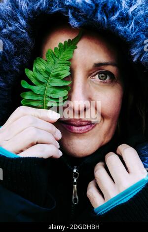 ritratto di una donna di 45 anni con una foglia di felce sopra un giorno d'autunno e d'inverno nella foresta Foto Stock