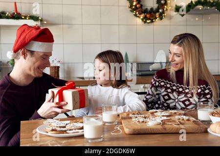 Papà felice che dà il regalo carino piccola figlia che celebra il Natale a casa. Foto Stock