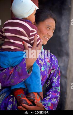 Madre Ladakhi in abito festivo che porta il bambino. Festival di Karsha Gustor, monastero di Karsha, vicino alla valle di Padum Zanskar, Ladakh, Jammu e Kashmir, India settentrionale Foto Stock