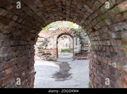 Tunnel arco edificio rovine vecchio edificio in mattoni con pavimento in cemento, frammento di catacombe Foto Stock