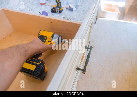 Installazione di maniglie per cassetti su armadi da cucina Foto Stock