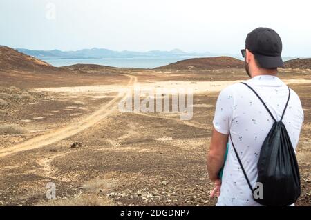 Giovane viaggiatore sul paesaggio deserteventura di Fuerteventura con l'oceano sullo sfondo. Foto Stock