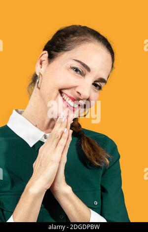 Una donna che indossa una camicia verde casual che prega con le mani insieme chiedere perdono sorridendo fiducioso Foto Stock