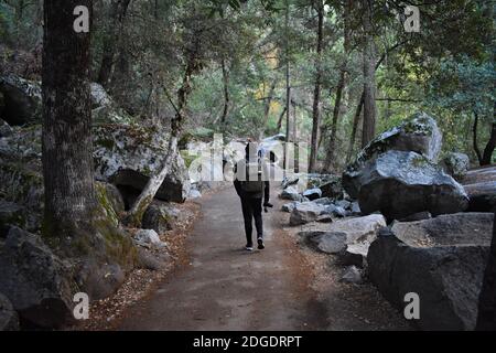 Un escursionista di sesso maschile che indossa uno zaino e porta con sé una macchina fotografica inizia a fare un'escursione lungo i sentieri John Muir e Mist nella Yosemite Valley, California, USA. Foto Stock