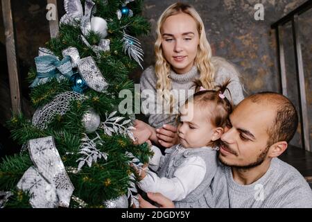 Felice famiglia decorare albero artificiale natale a casa insieme. Foto Stock