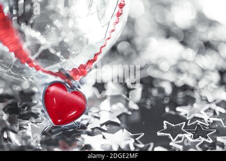 Macro foto di stella argentata brillante e sfera di vetro fessurata e cuore rosso Foto Stock