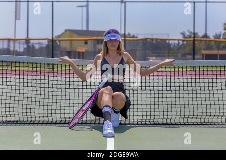 Un bel modello Blonde gioca a tennis su un caldo Summers Giorno Foto Stock