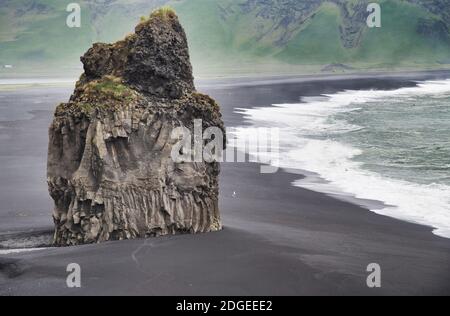 Giant Rock a Reynisfjara Black Beach in una nuvolosa mattina estiva, Islanda Foto Stock