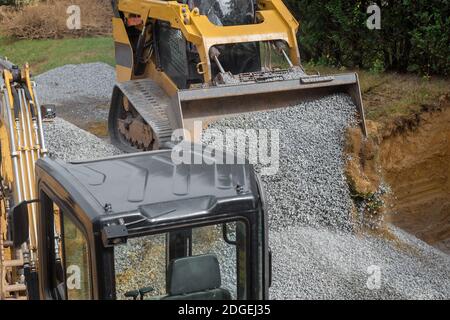 Primo piano escavatore lavorando in cantiere, la benna dell'escavatore livella la ghiaia sulle fondamenta dell'edificio Foto Stock