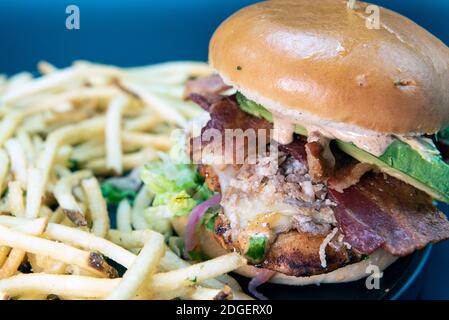 Alto ordine di sandwich di pollo avocado e patatine fritte caricate con tutti i condimenti che i conigli possono contenere Foto Stock