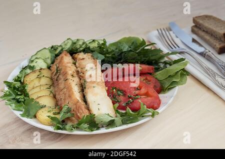 Pesce fritto con patate, verdure ed erbe aromatiche Foto Stock