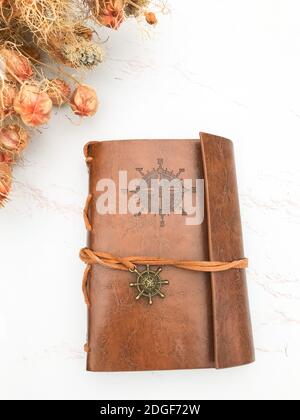 Fiori secchi e un notebook in pelle Foto Stock