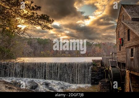 Una vista panoramica festosa del mulino a griglia presso lo storico Yates Mill County Park, Raligh, North Carolina, con spettacolari nuvole durante l'ora d'oro. Foto Stock