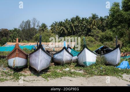 Barche da pesca sulla spiaggia sabbiosa vicino alla giungla in India Foto Stock