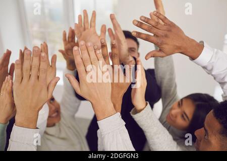 Team di giovani felici uomini d'affari misti che alzano le mani in alto nell'aria Foto Stock