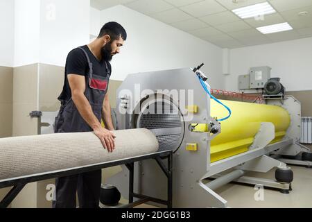 Uomo che aziona la macchina asciugatrice per la pulizia dei tappeti. Servizio  di pulizia professionale dei tappeti Foto stock - Alamy