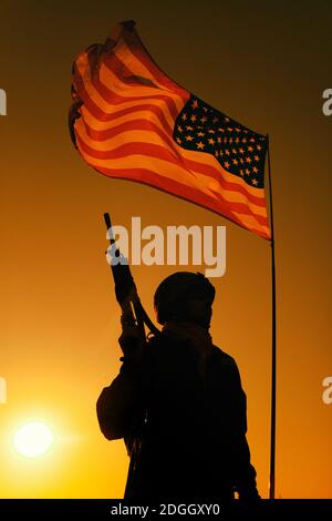 Silhouette del soldato di fanteria dell'esercito americano, veterano di fucile da guerra delle forze speciali, fucile d'assalto armato in piedi sotto la bandiera nazionale degli Stati Uniti d'America sventolando il sole sullo sfondo Foto Stock