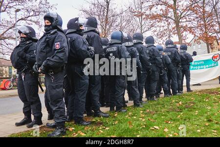 Braunschweig, Germania, 05 dicembre 2020: Gruppo di poliziotti tedeschi in uniforme nera con casco, visiera, baton, che si fissano su due lati Foto Stock