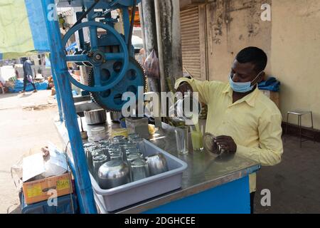 Goa India 11 novembre 2020 UN venditore di strada che versa canna da zucchero Spremere in bicchiere al Mapusa Market Goa Foto Stock