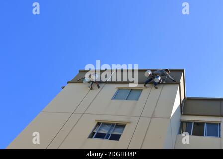 Bangkok, Thailandia - 9 dicembre 2020: I lavoratori stanno riparando la parete incrinata all'esterno di un edificio alto usando silicone sigillante e poi verniciando Foto Stock