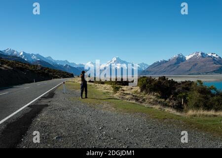 Turista che scatta le foto del telefono cellulare di Mt Cook sul lato della strada Foto Stock