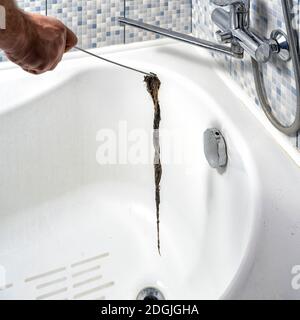 scarico intasato in bagno. un idraulico estrae un coagulo di sporco con un utensile Foto Stock